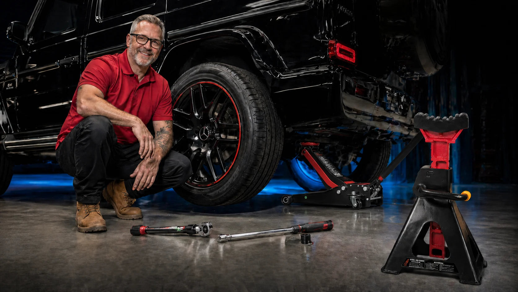 Mechanic beside a premium four-wheel drive supported by workshop lifting gear